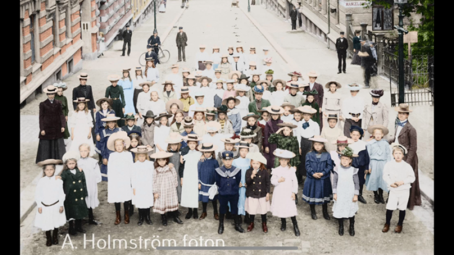 Folksamling på Nedre Fogelbergsgatan 1899 - foto: A W Olsson. .Färglagd av hans barnbarns barnbarn Andreas Holmström, 2023.